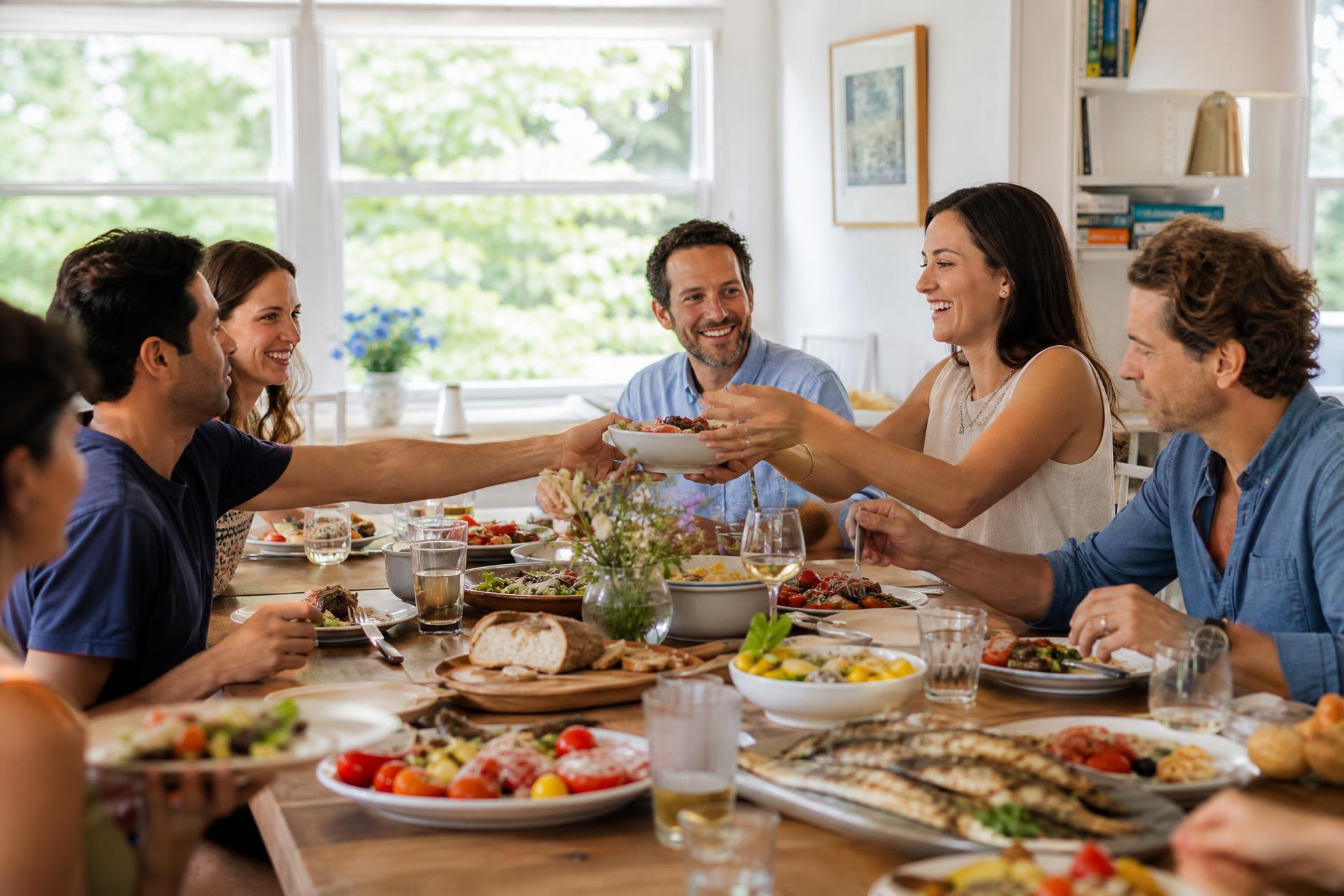 Friends gathered around a sunlit New England dinner table sharing family-style dishes
